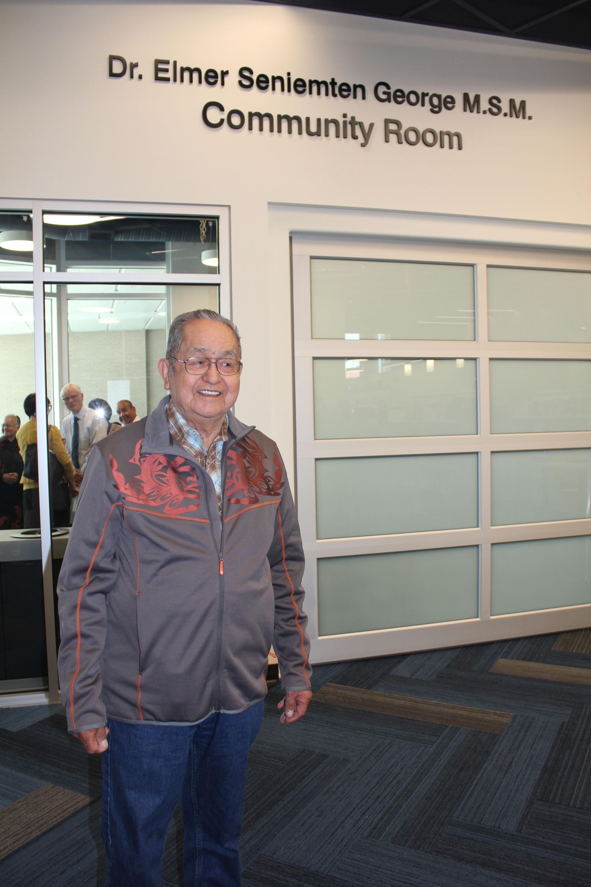Dr. Elmer Seniemten George standing outside the community room named in his honour at the James Bay Library Branch